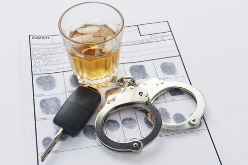 Handcuffs, car keys, and a glass of alcohol on ice representing an impaired driving conviction in Canada